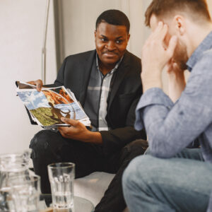 Two men discussing while one shows a magazine page.