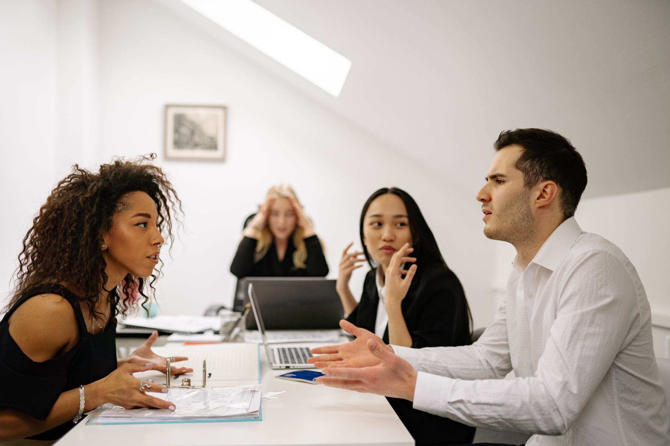 A diverse group engaged in a serious business meeting in a bright office.
