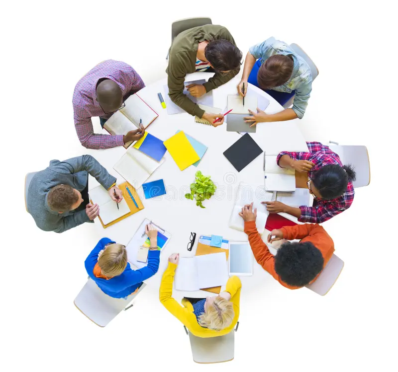 A diverse group collaborating around a table with documents and devices.