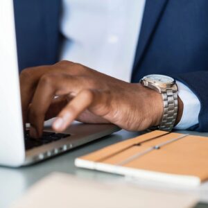 Close-up of a person typing on a laptop keyboard at a desk.